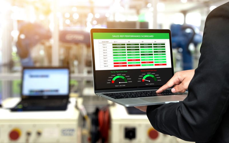 Male manager hand suit using laptop with machine real time monitoring sale rep performance scorecard system software. Blur robot arm machine in smart factory. Industry 4th iot , digital manufacturing.